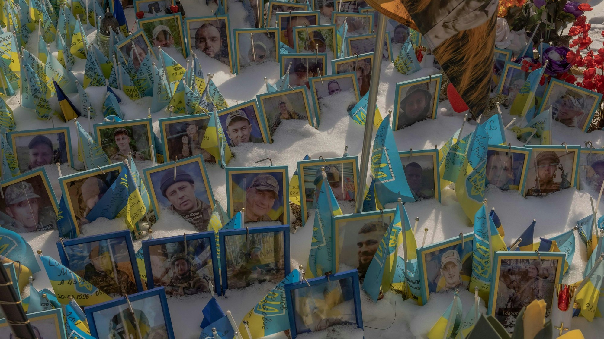 TOPSHOT - This photograph taken on February 23, 2025, shows portraits of soldiers in snow at the makeshift memorial paying tribute to Ukrainian and foreign fighters at the Independence Square in Kyiv, on February 23, 2025, ahead of the third anniversary of Russia's invasion of Ukraine. (Photo by Roman PILIPEY / AFP)