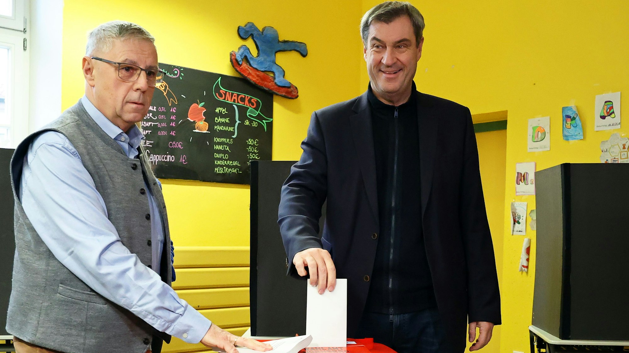Markus Söder (CSU, r), Ministerpräsident von Bayern, gibt in einem Wahllokal in einer Schule in Nürnberg seine Stimme ab.