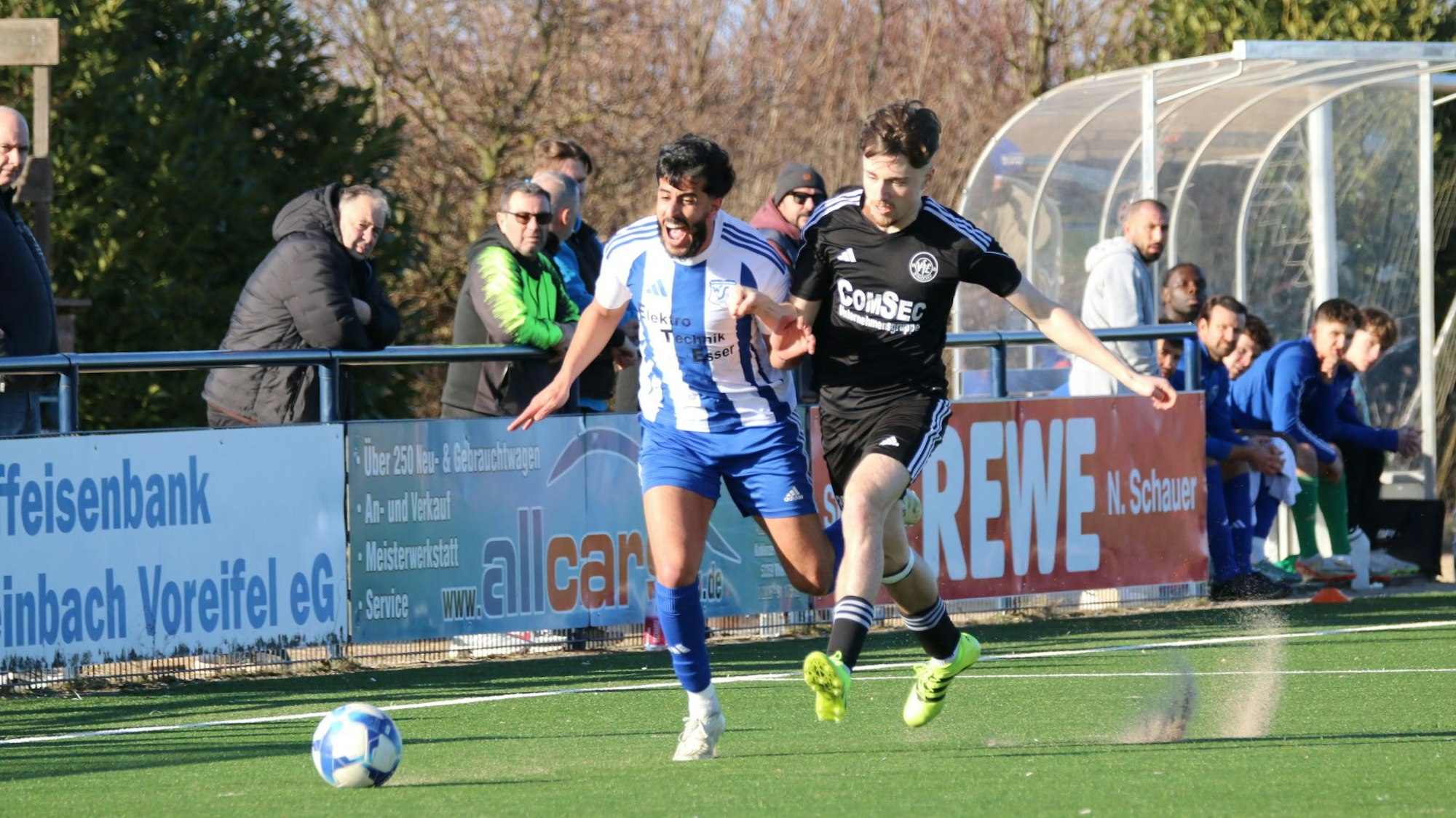Zwei Fußballer im Laufduell hinter dem Ball.