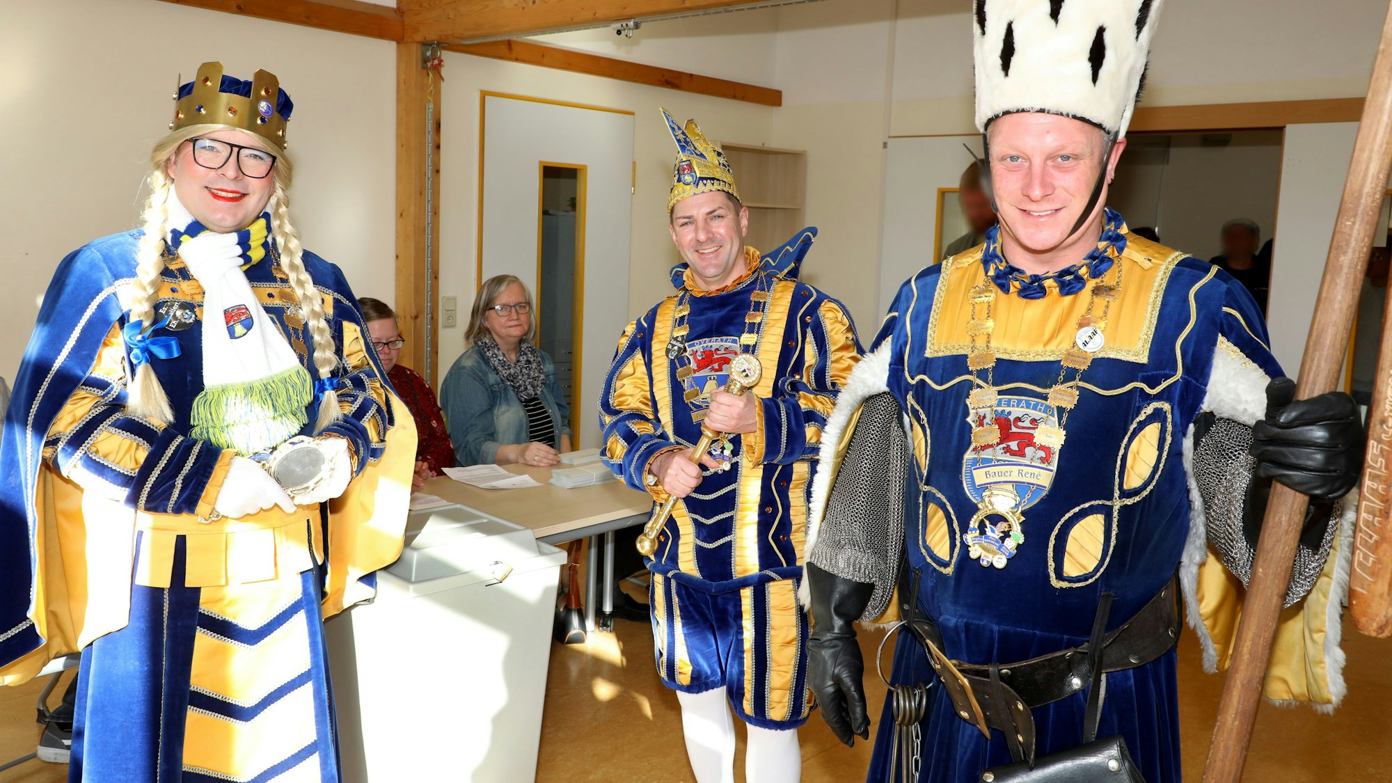 Das Overather Dreigestirn steht neben einer Wahlurne im Wahllokal in der Vilkerather Grundschule.