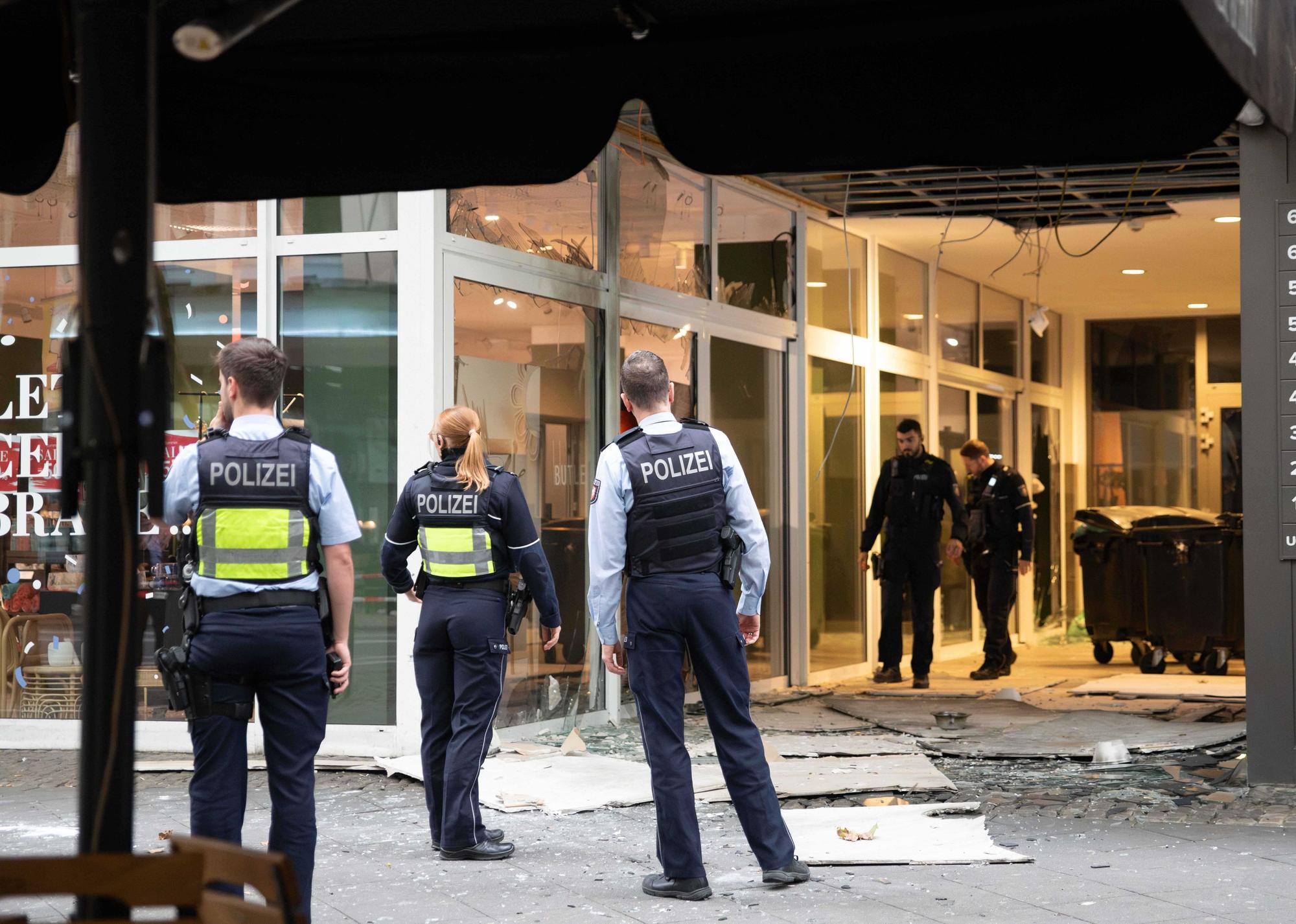 Das Foto zeigt Polizeibeamte, die nach einer Explosion vor einem beschädigten Gebäude in der Innenstadt am Hohenzollernring stehen.