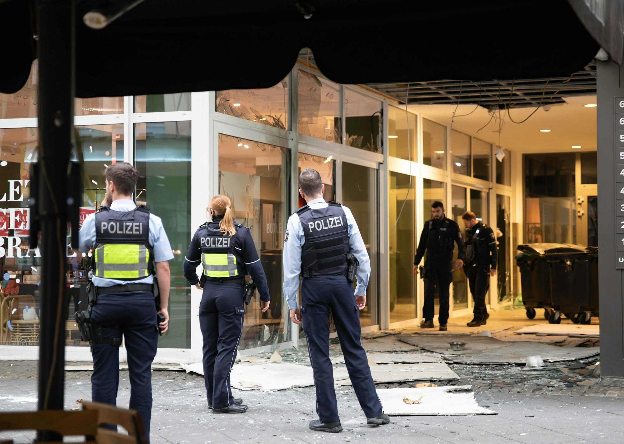 Das Foto zeigt Polizeibeamte, die nach einer Explosion vor einem beschädigten  Gebäude in der Innenstadt am Hohenzollernring stehen.
