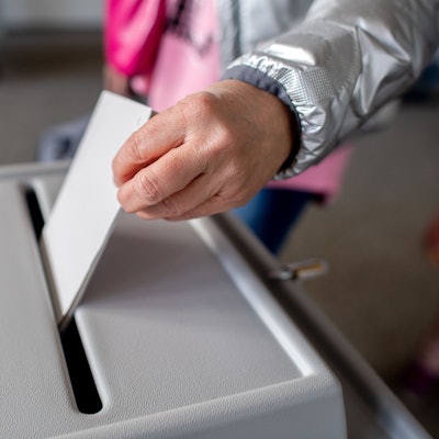 Eine Wählerin wirft in einem Wahllokal einen Stimmzettel in eine Wahlurne.