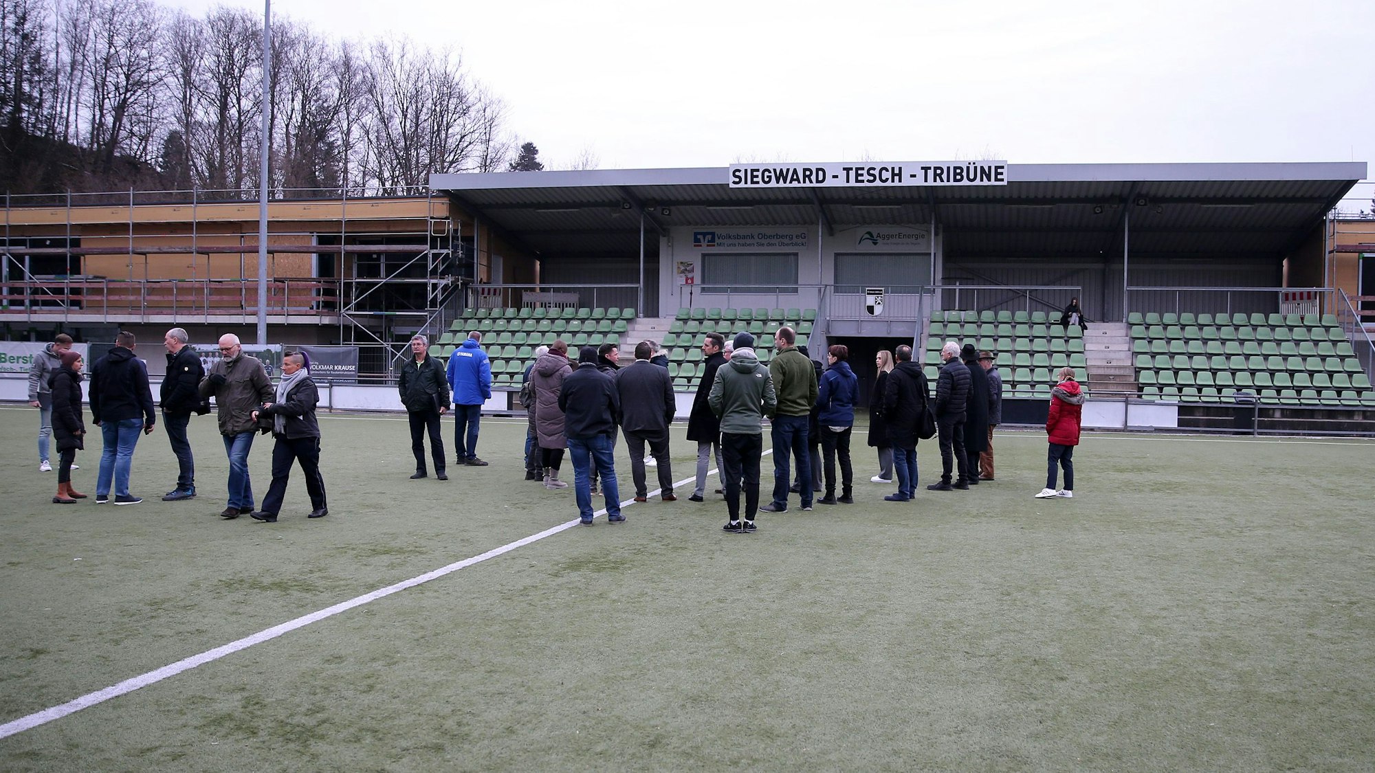 Eine Gruppe steht auf dem Rasen einer Sportanlage.