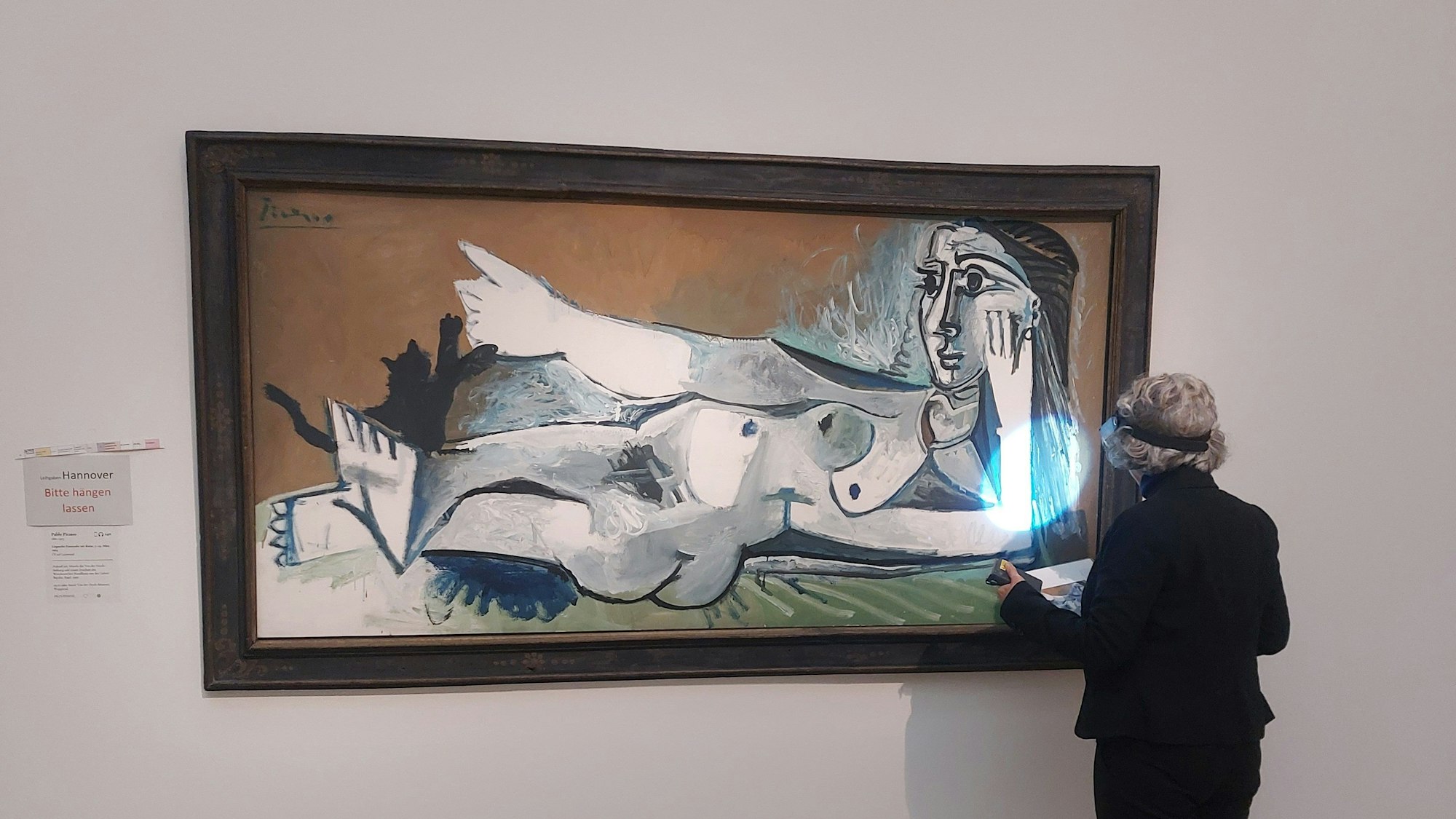 Eine Frau im dunklen Anzug steht mit dem Rücken zum Betrachter vor einem großformatigen Gemälde von Picasso.