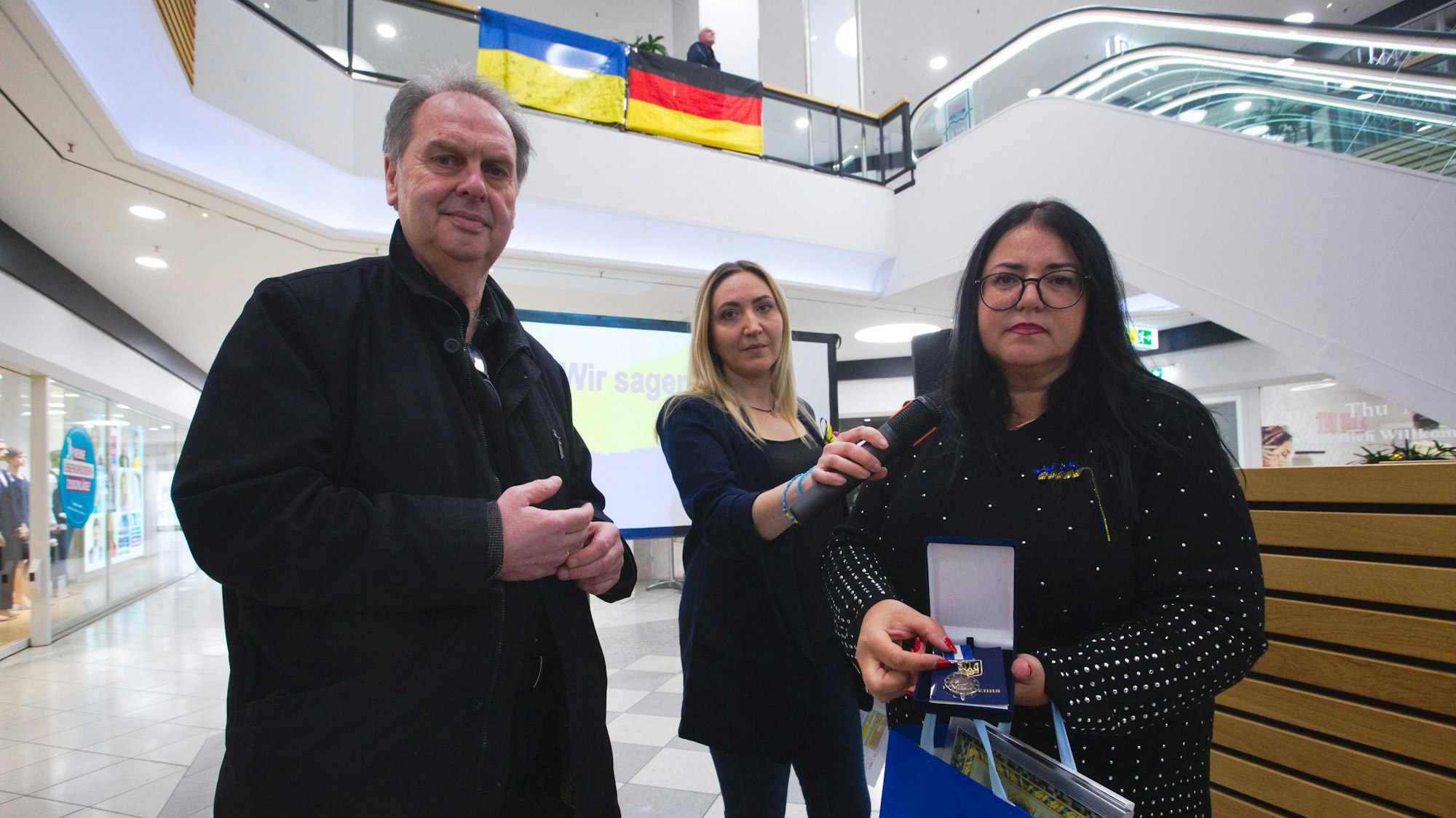 Ein Mann erhält von zwei Frauen eine Urkunde und einen ukrainischen Orden.