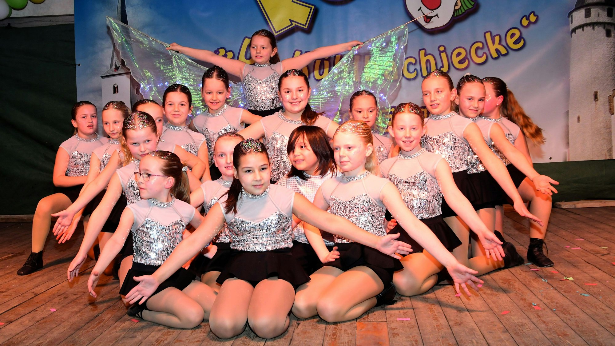Die jungen Tänzerinnen des Karnevalsvereins Lessenich hocken in schwarz-silbernen Kostümen auf der Bühne.
