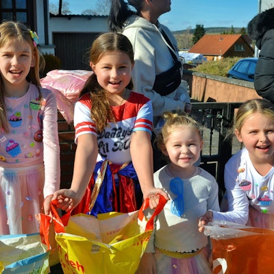 Vier kostümierte Mädchen stehen nebeneinander und breiten ihre Plastiktüten aus.