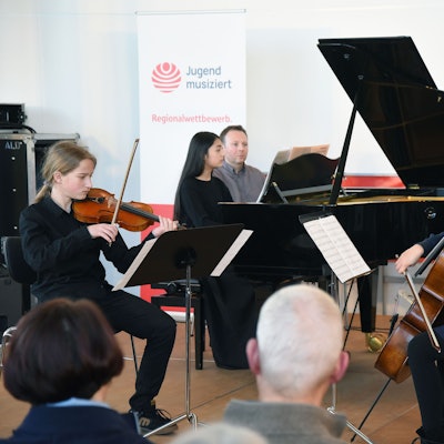 Das Foto zeigt drei junge Musikerinnen und Musiker.