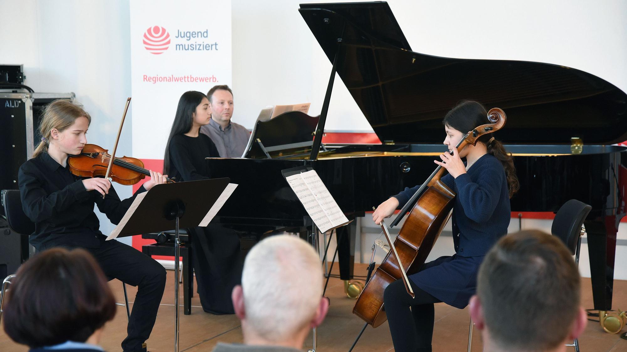 Das Foto zeigt drei junge Musikerinnen und Musiker.