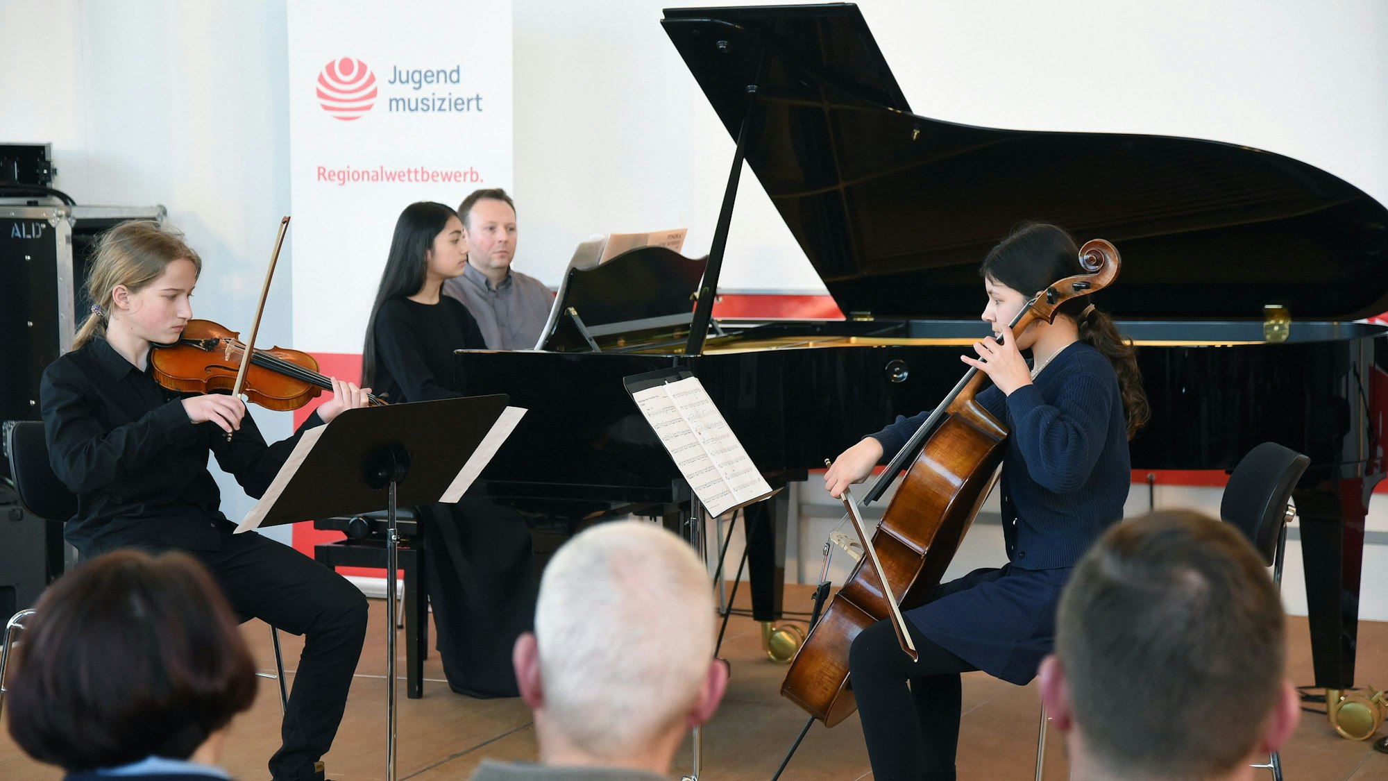 Das Foto zeigt drei junge Musikerinnen und Musiker.