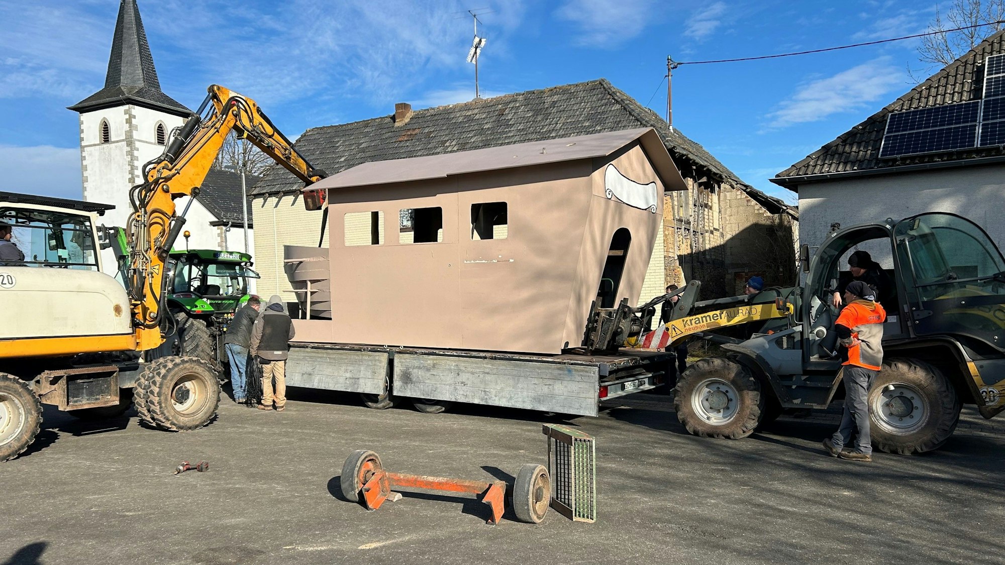 Zwei Frontlader stehen an einem Karnevalswagen in Nettersheim-Roderath, um den Aufbau auf einen anderen Anhänger umzuladen.