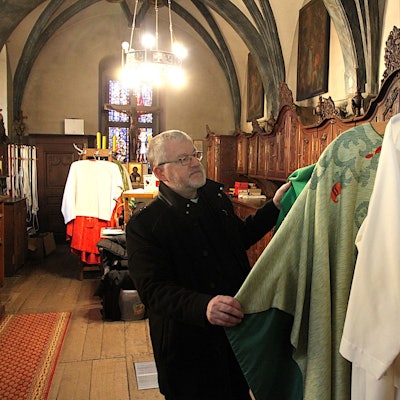 Der Steinfelder Pfarrer Wieslaw Kaczor steht in der Sakristei der Basilika und schaut sich Messgewänder an.