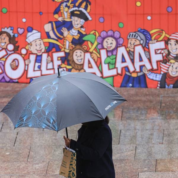 Eine Frau geht mit Regenschirm an einer Tribüne für die Karnevalsumzüge durch die Düsseldorfer Innenstadt. (Archivbild)