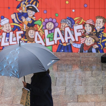 Eine Frau geht mit Regenschirm an einer Tribüne für die Karnevalsumzüge durch die Düsseldorfer Innenstadt. (Archivbild)