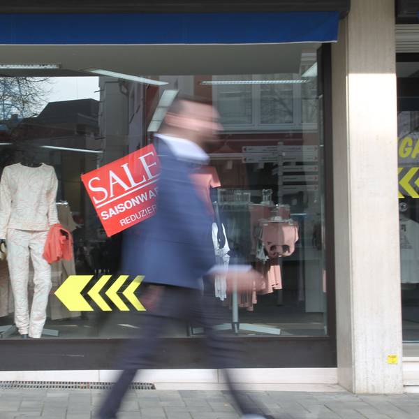 Zwei Männer gehen an einem Schaufenster vorbei.