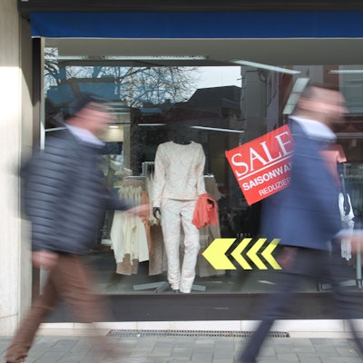 Zwei Männer gehen an einem Schaufenster vorbei.