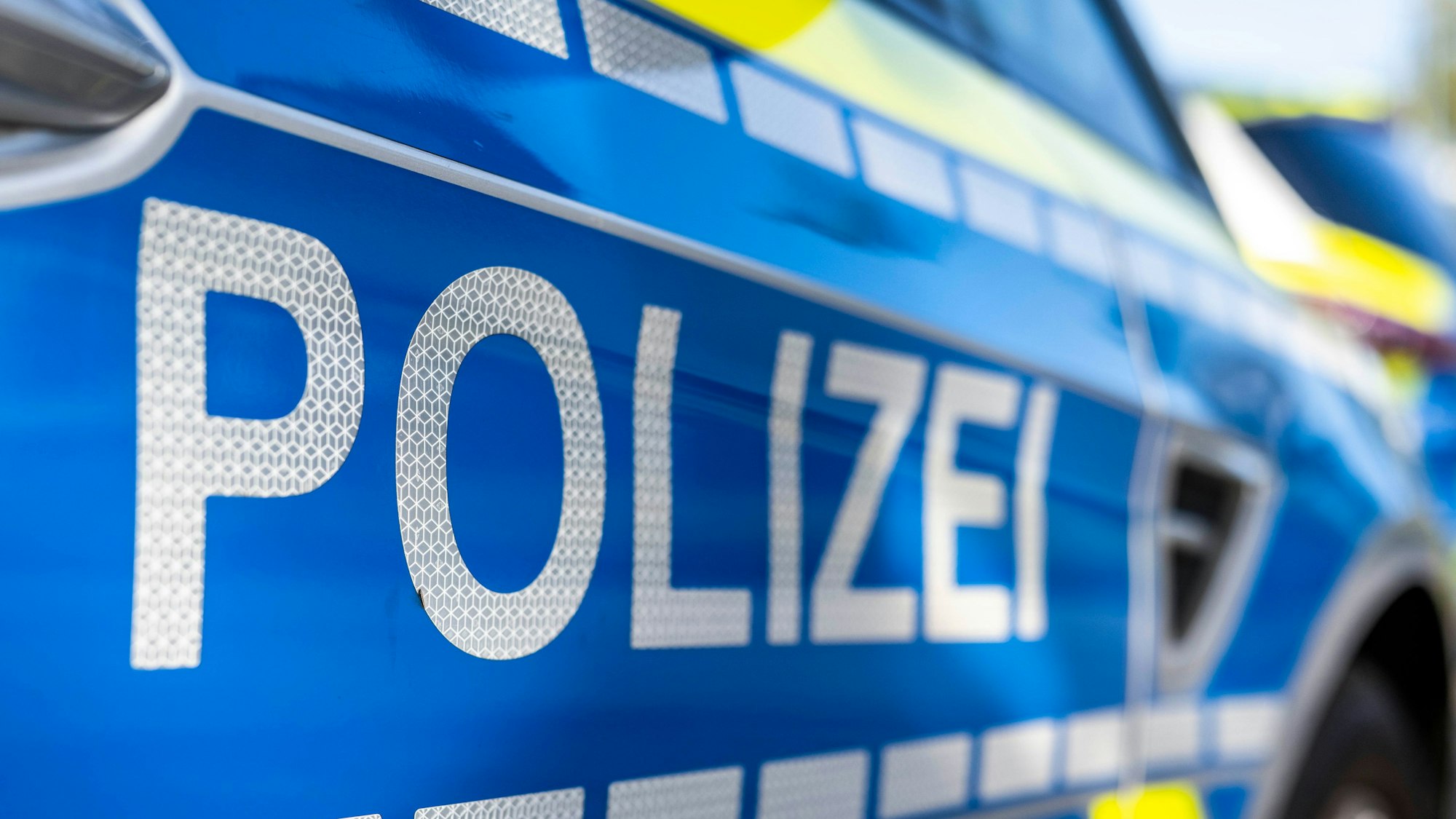 An der Tür von einem Streifenwagen steht der Schriftzug „Polizei“.
