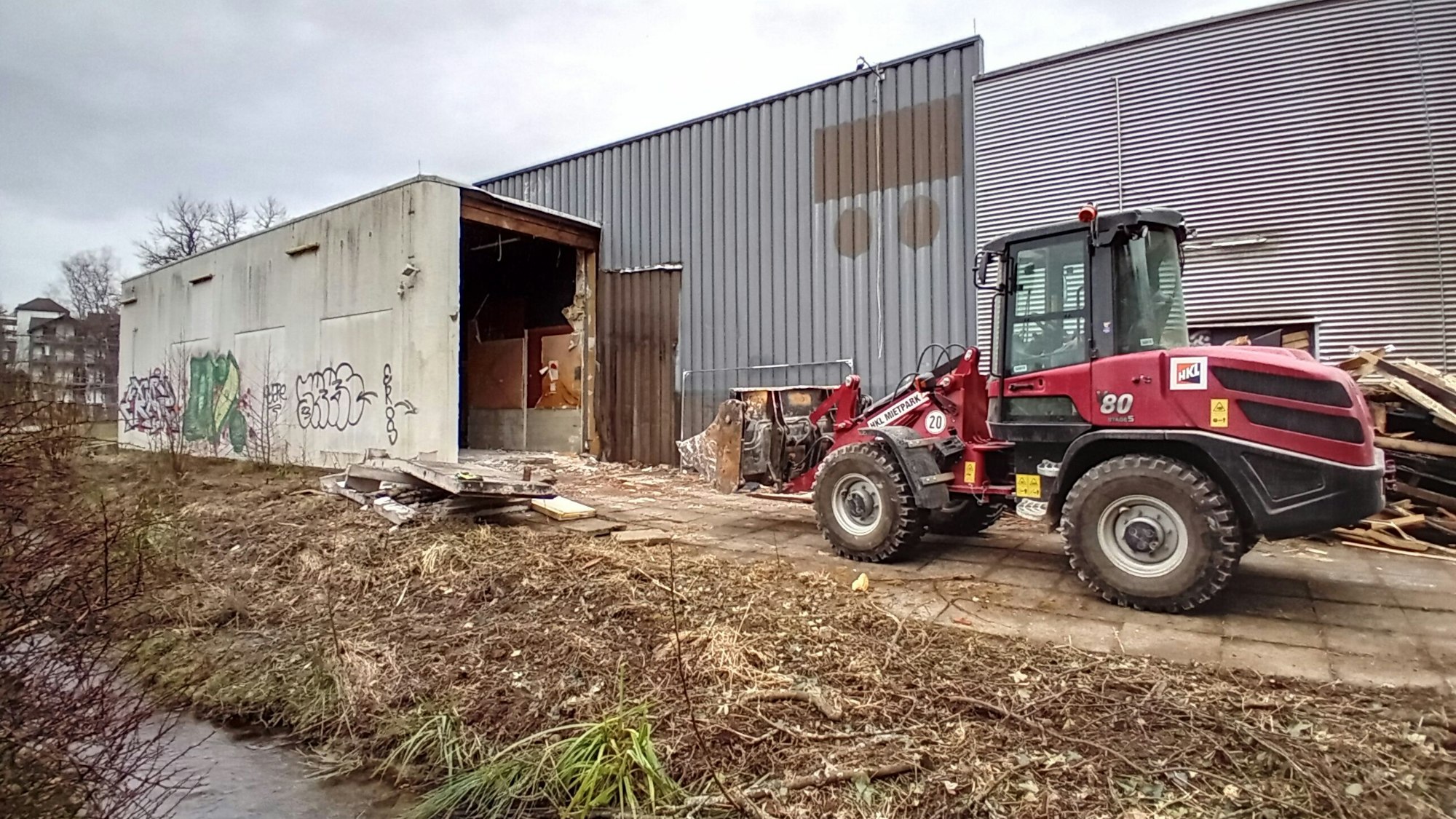 Ein Bagger vor einer Industriehalle.
