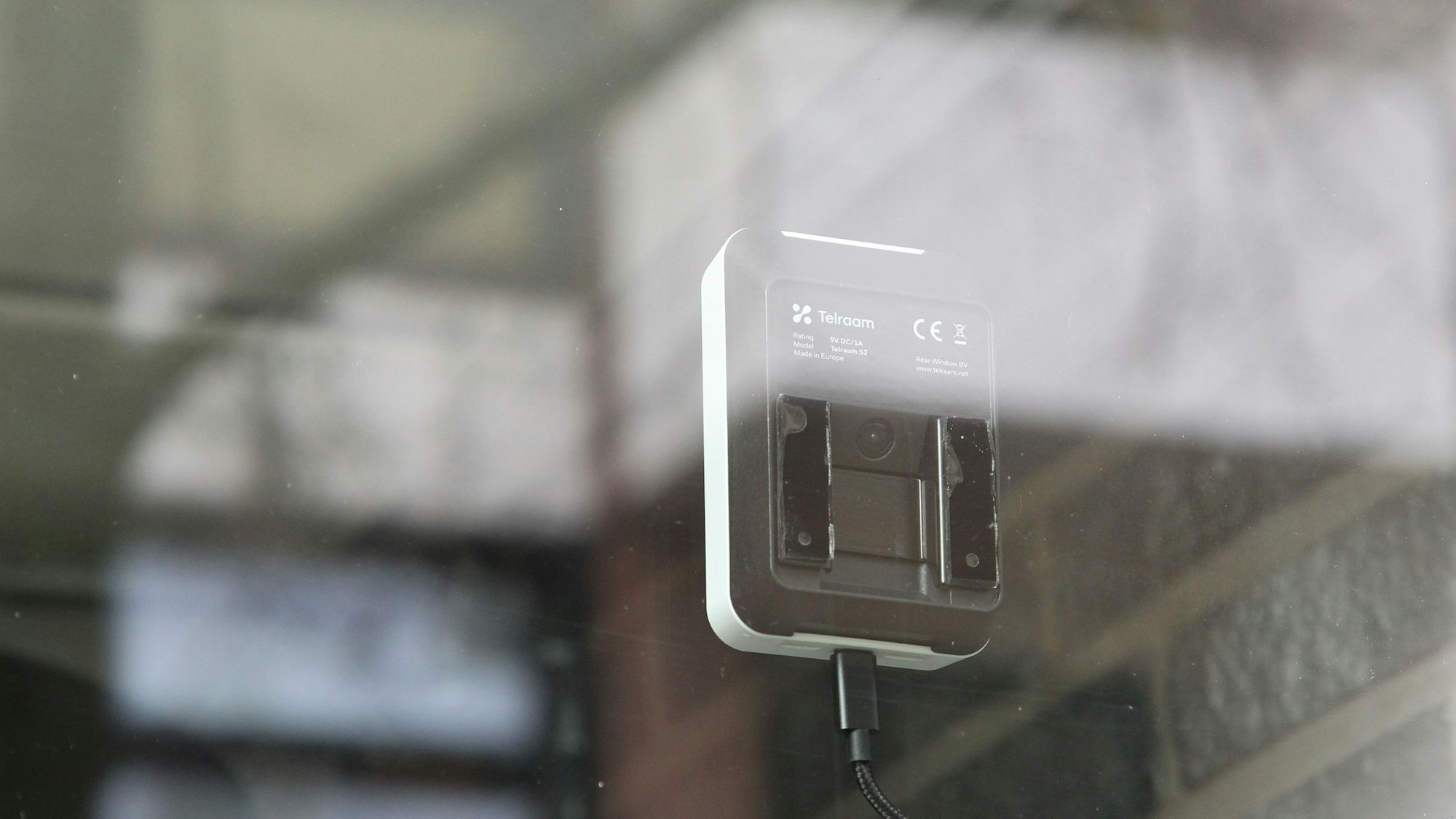 Hinter einer Schaufensterscheibe ist ein kleines Messgerät mit Sensor montiert.