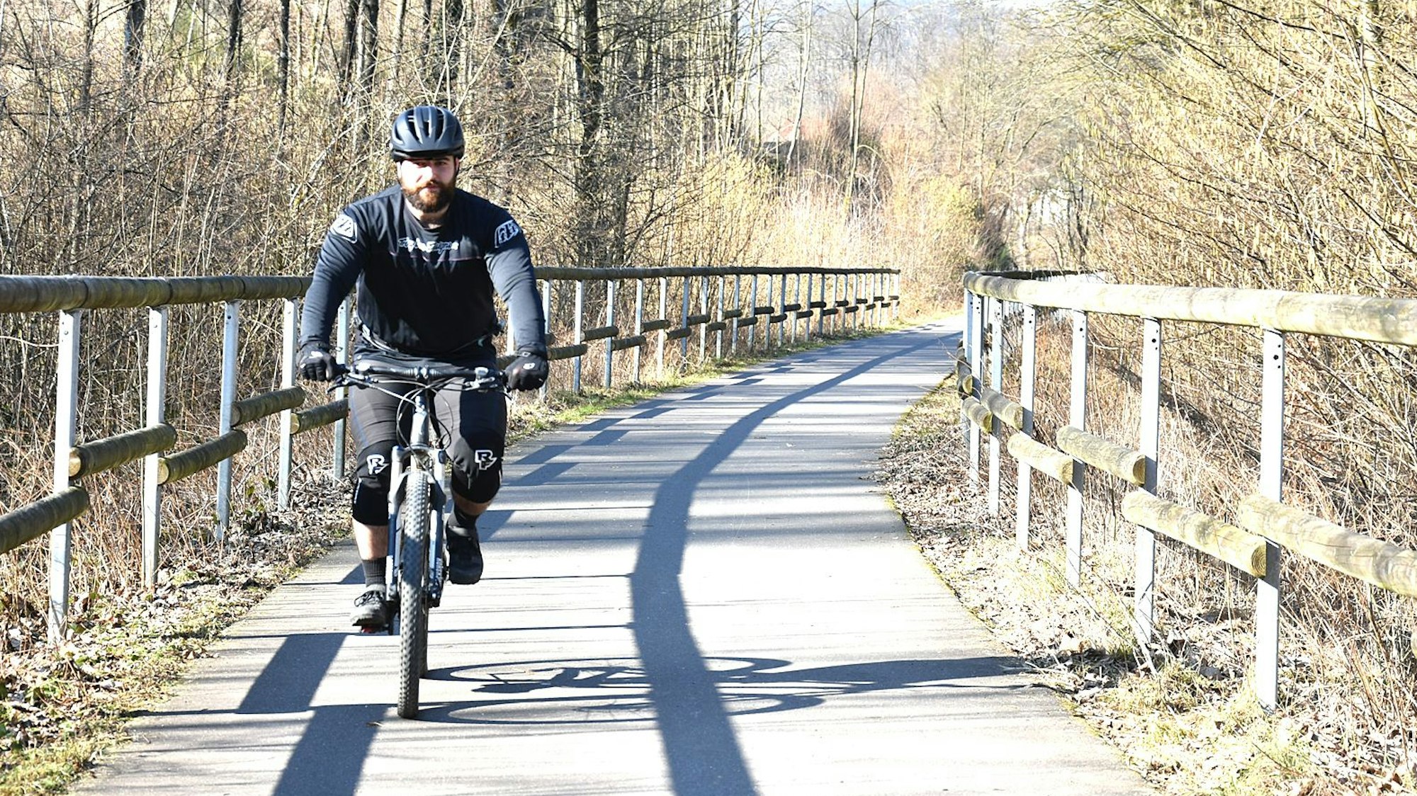 Ein Mann fährt mit einem Fahrrad auf einer alten Bahntrasse.