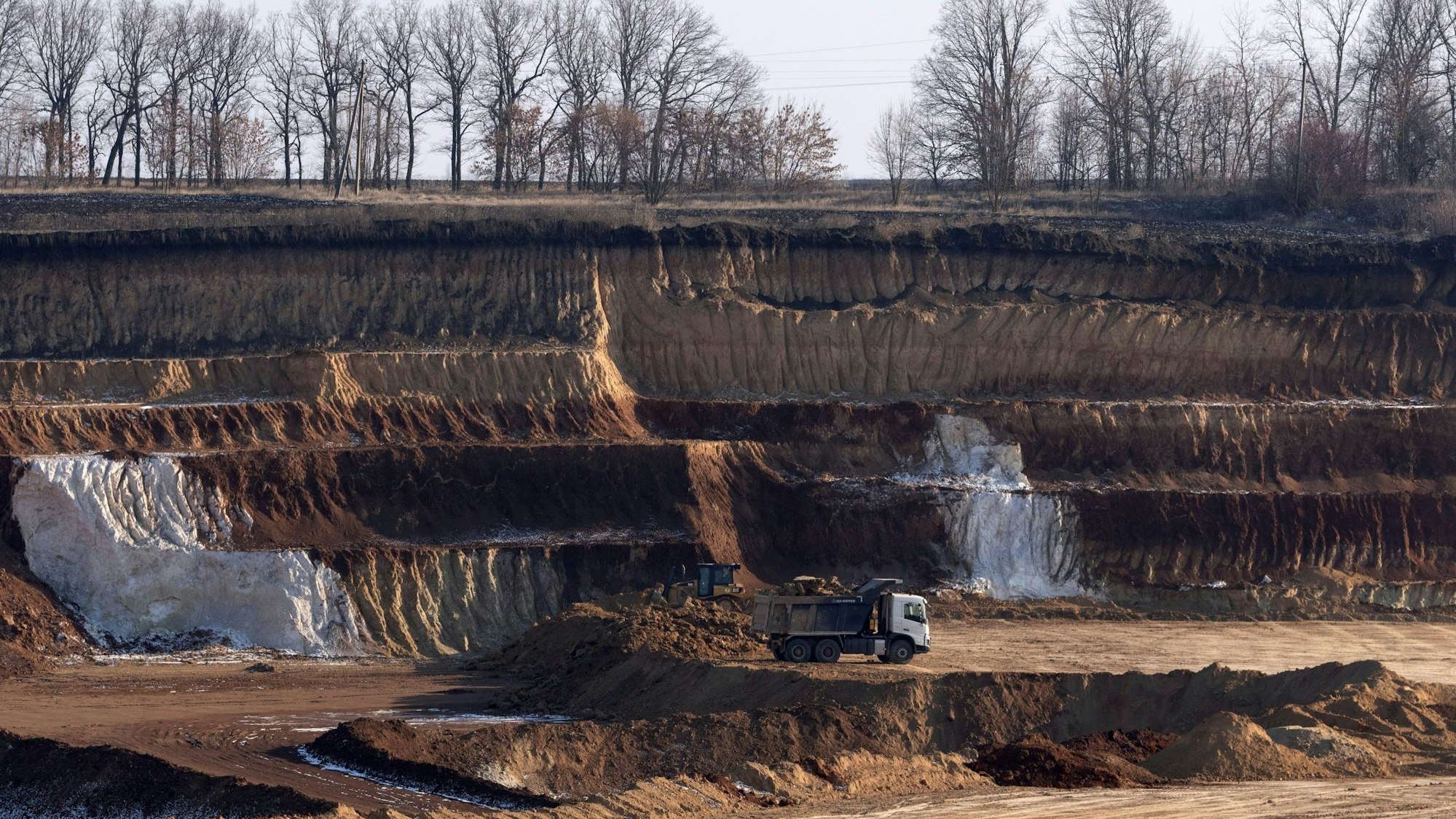 12.02.2025, Ukraine, Kirowohrad: Ein LKW transportiert eine Ladung in einem Ilmenit-Tagebau in einer Schlucht in der Region Kirowohrad.