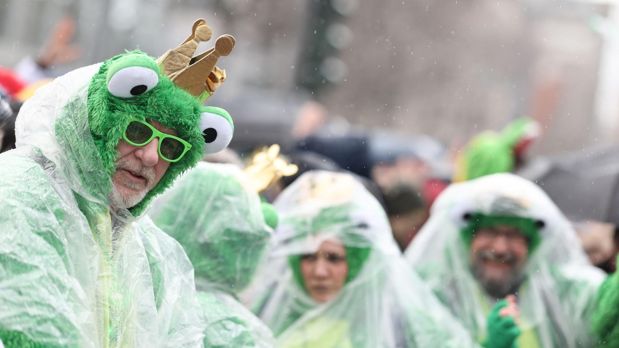 ARCHIV - 12.02.2024, Nordrhein-Westfalen, Köln: Karnevalisten schützen sich vor Regen während des Rosenmontagsumzugs. Mit den Rosenmontagszügen erreicht der rheinische Straßenkarneval seinen Höhepunkt. Das Motto der Kölner Karnevalssession 2024 lautet "Wat e Theater - wat e Jeckespill".
In Köln waren gleich mehrere Frösche zu sehen. (zu dpa: «Wechselhaftes Wetter in Rheinland-Pfalz und Saarland») Foto: Rolf Vennenbernd/dpa +++ dpa-Bildfunk +++