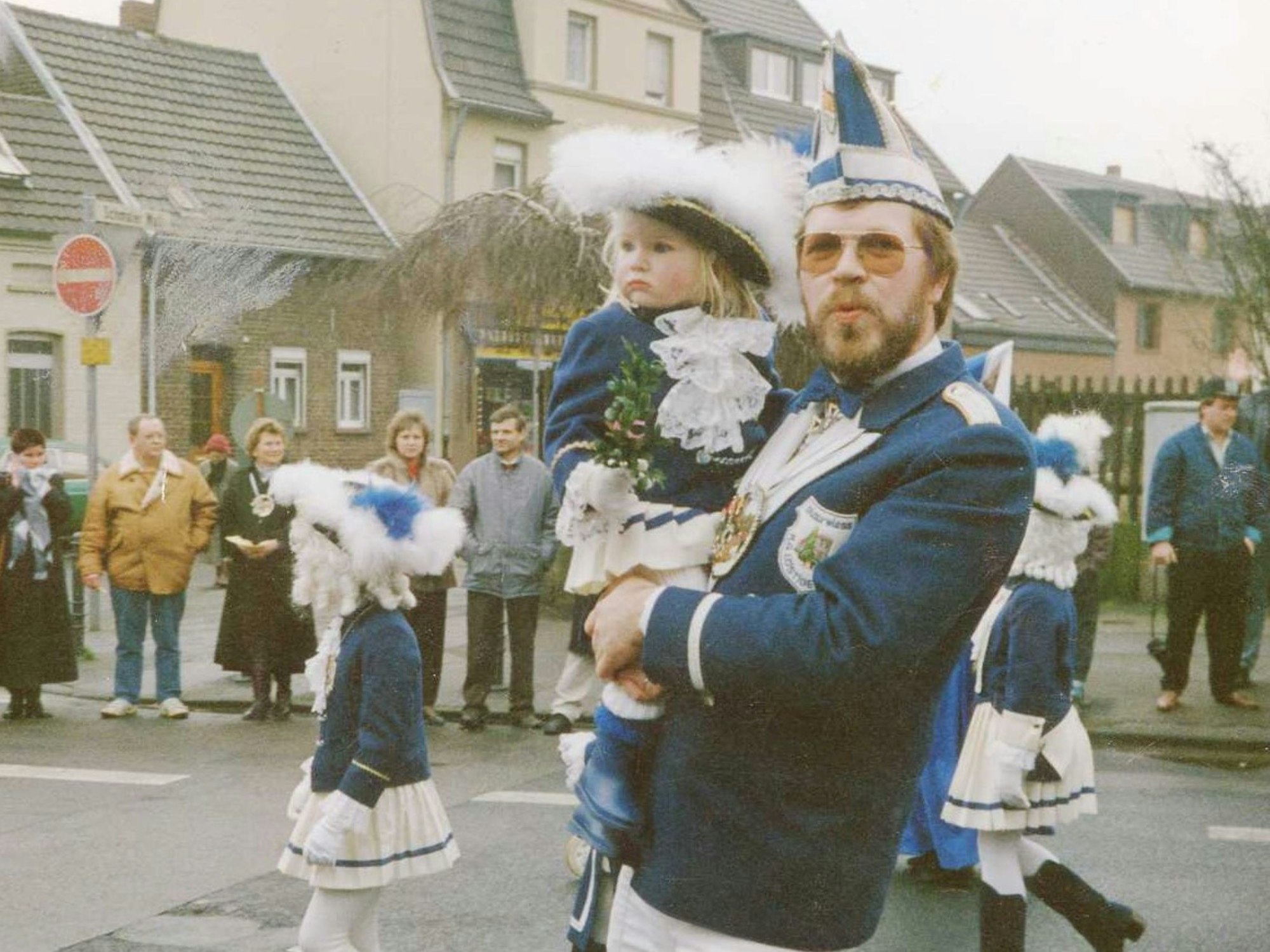 Ein Mann trägt beim Karnevalszug in Engelskirchen seine kleine Tochter auf dem Arm.