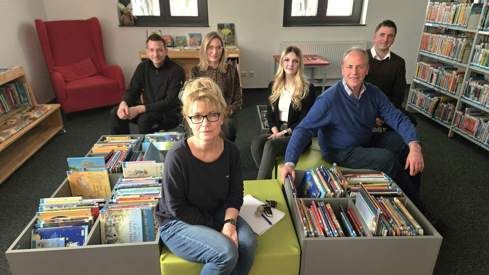 Florian Marx, Anja Schlösser, Nina Pützer, Michelle Dahm, Hermann-Josef Esser und André Kaudel sitzen auf Hockern in der Kinderbuchabteilung der Gemeindebibliothek.