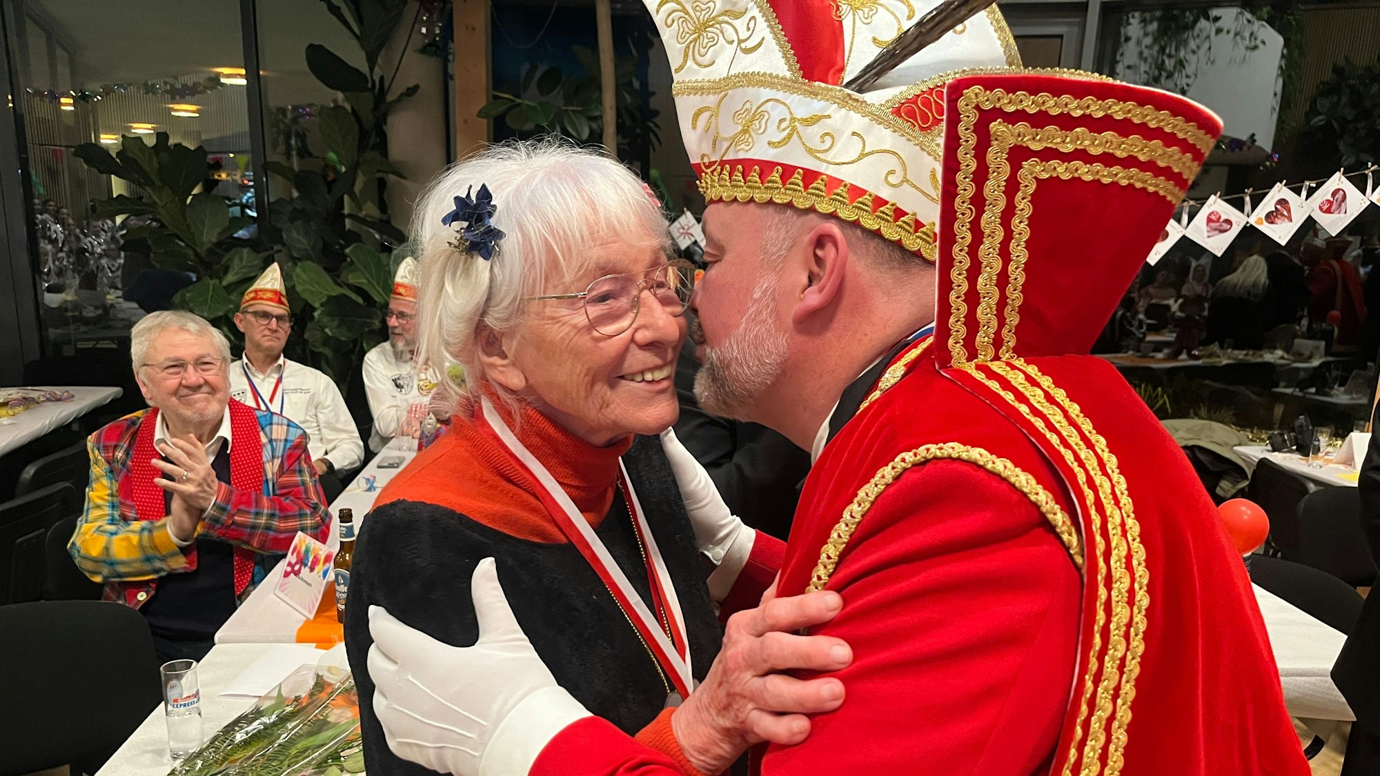 Ein Karnevalsprinz bützt eine ältere Frau.