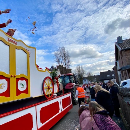 Zu sehen sind ein Karnevalswagen und Zuschauer am Straßenrand.