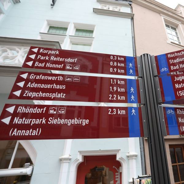 Auf roten Tafeln stehen Richtungsangaben und Entfernungen zu Zielen in der Stadt Bad Honnef.