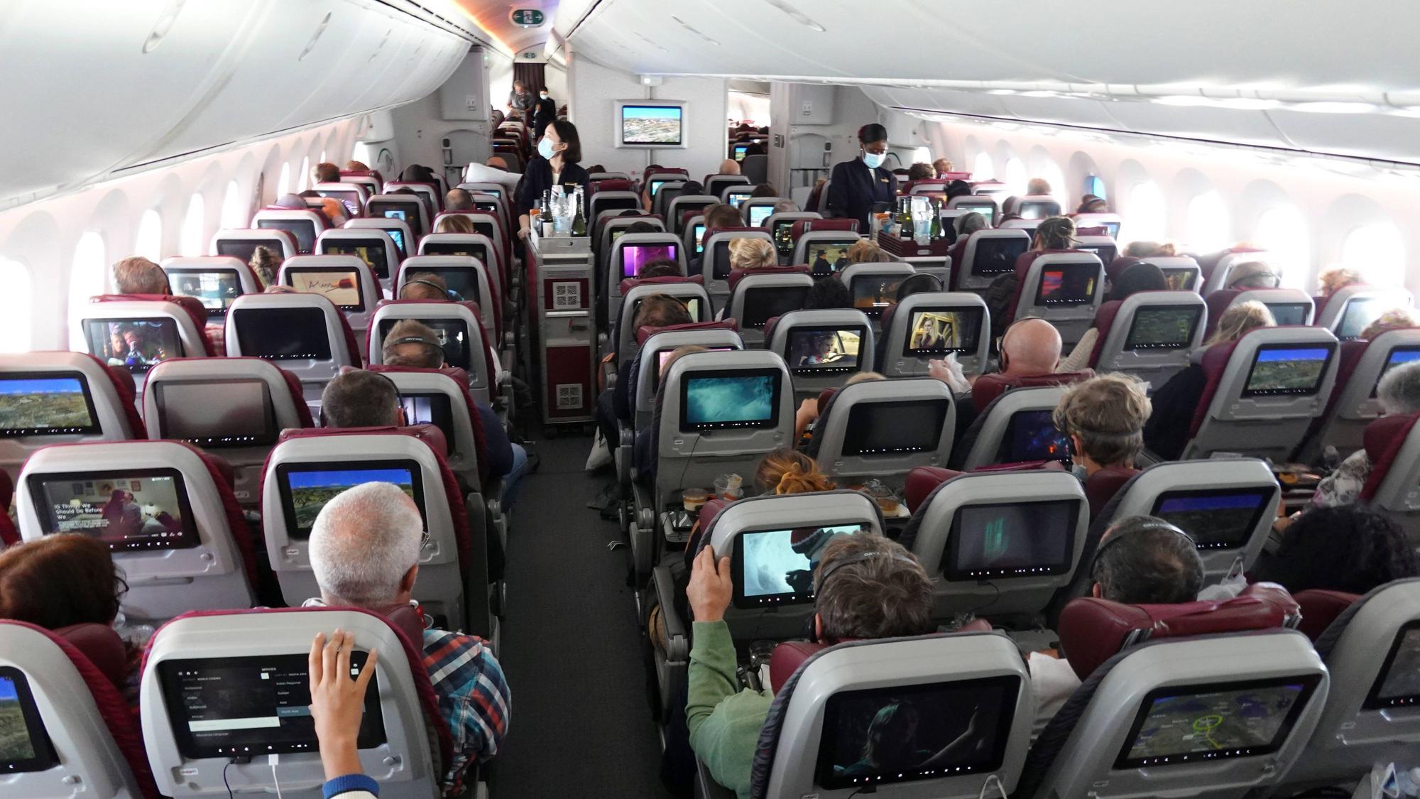 Passagiere und Flugbegleiter in einer Flugzeugkabine.
