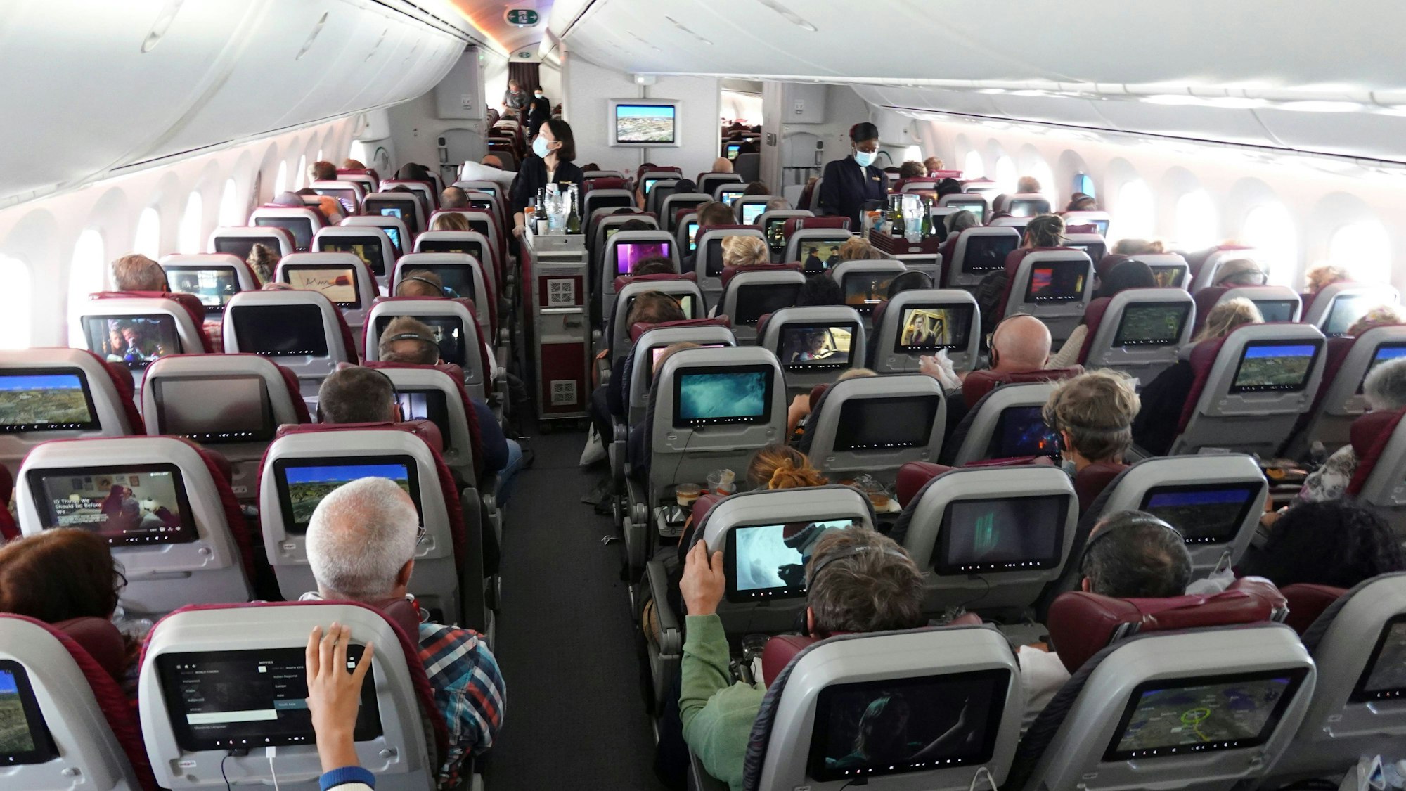 Passagiere und Flugbegleiter in einer Flugzeugkabine.