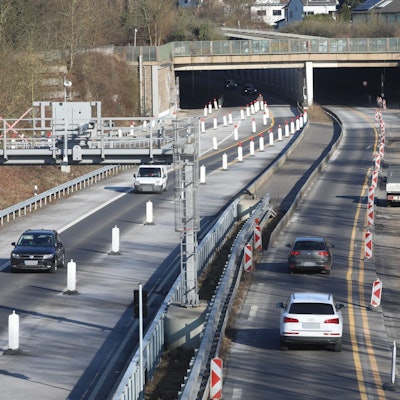 Eine Großbaustelle auf einer vierspurigen Straße, im Hintergrund die Einfahrt in einen Tunnel.