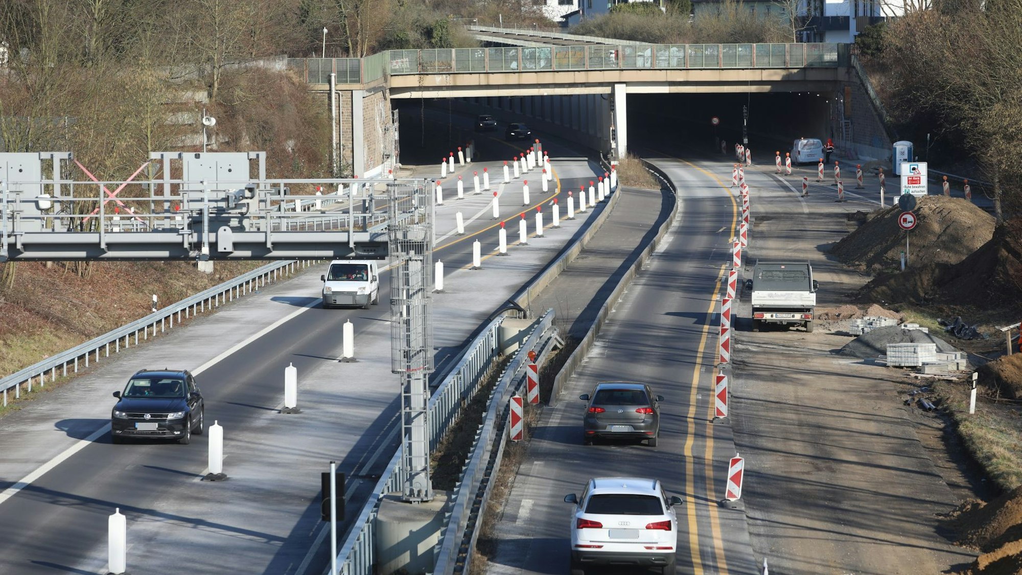 Eine Großbaustelle auf einer vierspurigen Straße, im Hintergrund die Einfahrt in einen Tunnel.