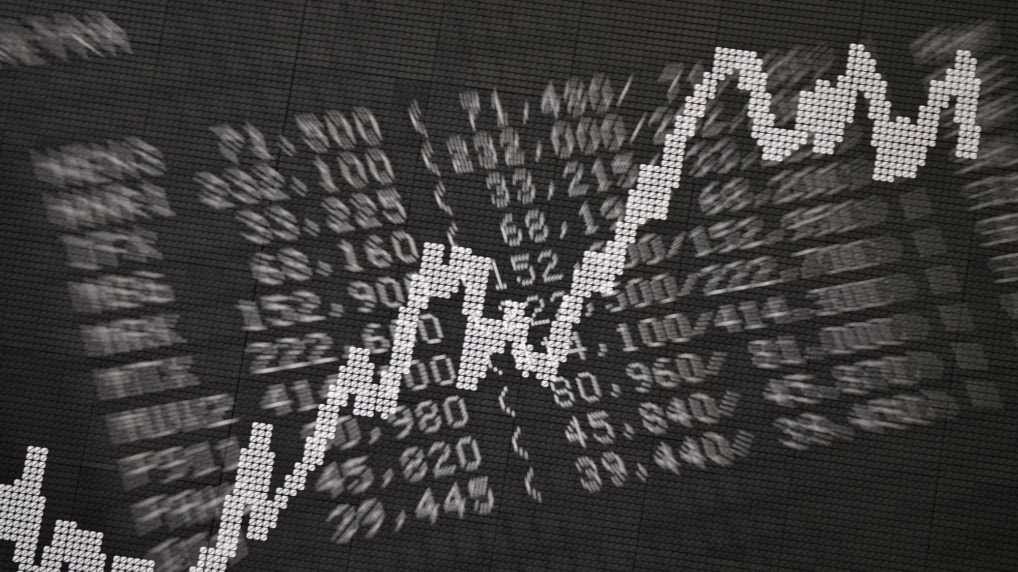 Die Doppelbelichtung zeigt eine Anzeigetafel im Handelssaal der Frankfurter Wertpapierbörse mit Kursen von Unternehmen im Xetra-Handel sowie der Dax-Kurve