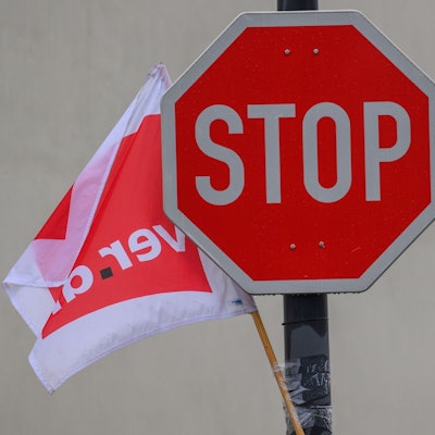 Eine Fahne der Gewerkschaft Verdi weht neben einem Stoppschild.