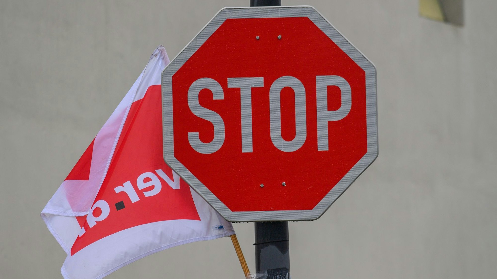 Eine Fahne der Gewerkschaft Verdi weht neben einem Stoppschild.