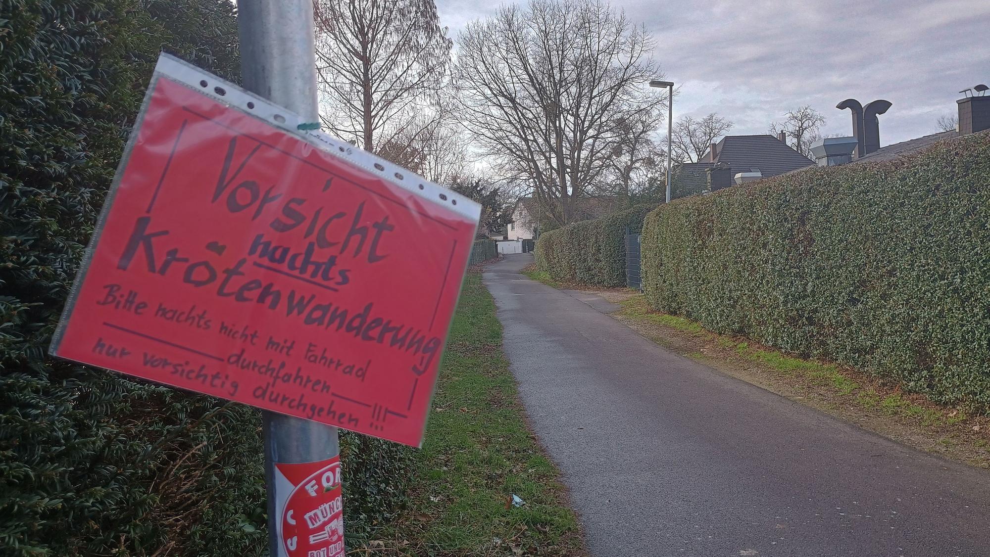 Auf dem roten Schild steht: „Vorsicht. Nachts Krötenwanderung. Bitte nachts nicht mit dem Fahrrad durchfahren. Nur vorsichtig durchgehen.“