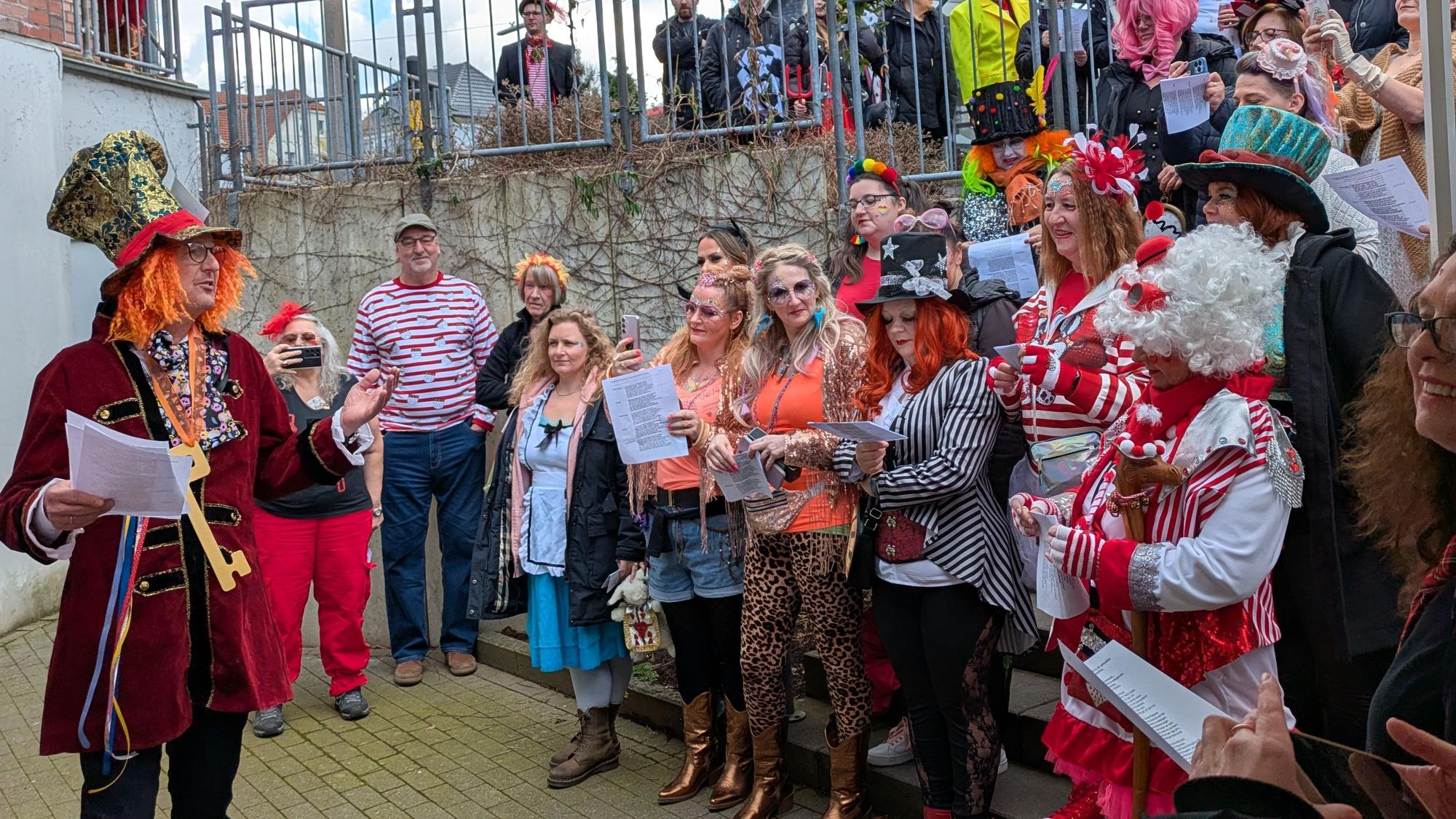 Eine Gruppe kostümierter Frauen steht vor einem Mann auf einer Treppe.