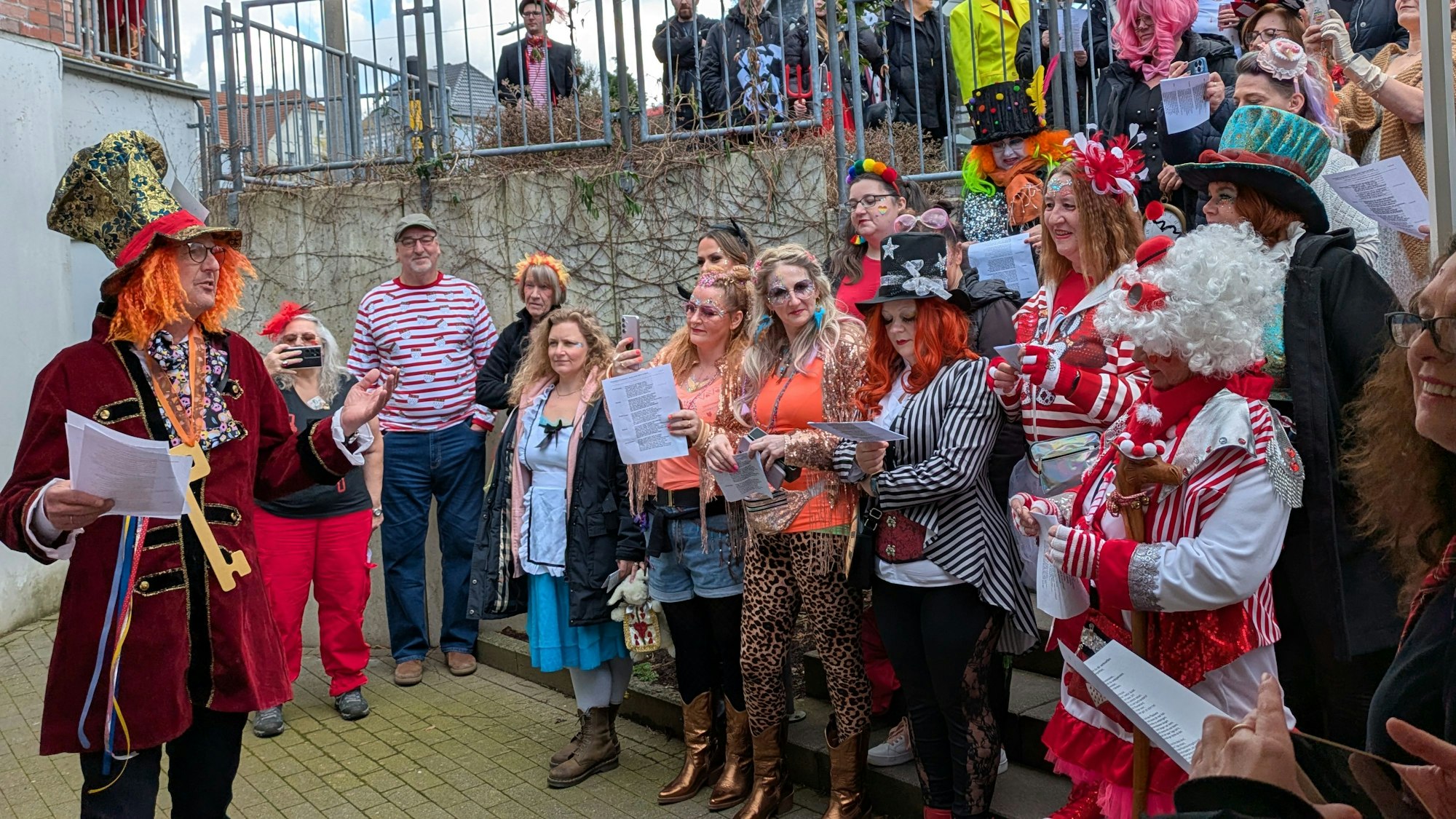 Eine Gruppe kostümierter Frauen steht vor einem Mann auf einer Treppe.