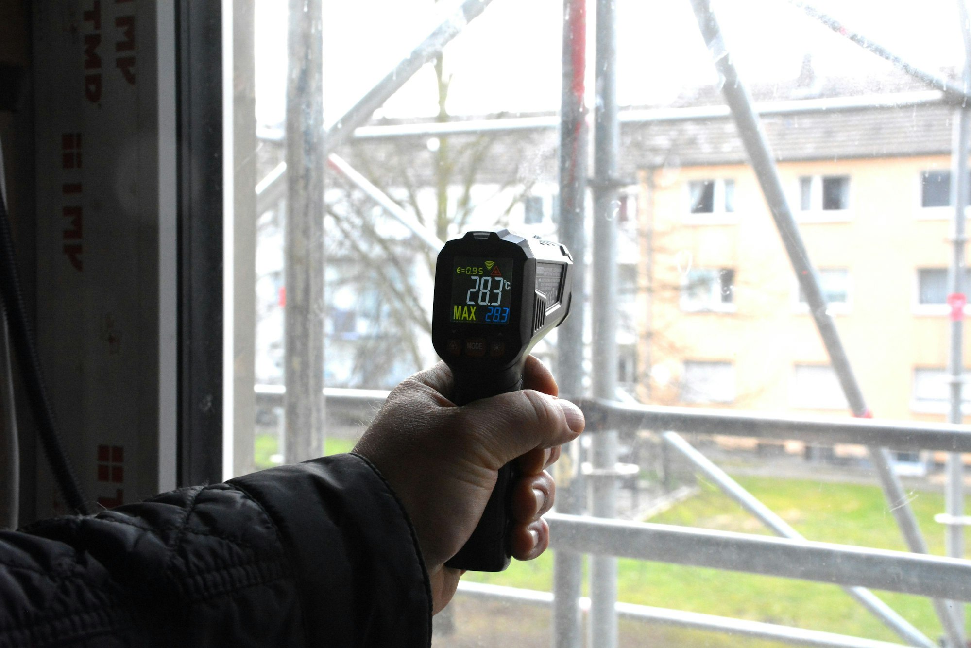 Ein Mann misst die Temperatur einer Fensterscheibe.