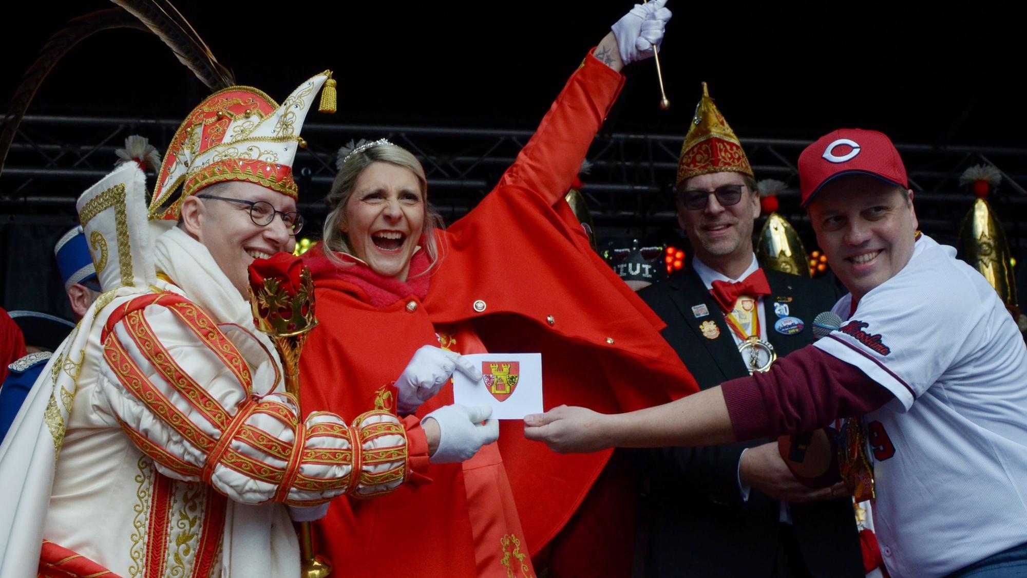 Das Euskirchener Prinzenpaar jubelt, als es von Bürgermeister Sacha Reichelt in einem Umschlag mit dem Stadtwappen den Schlüssel erhält.