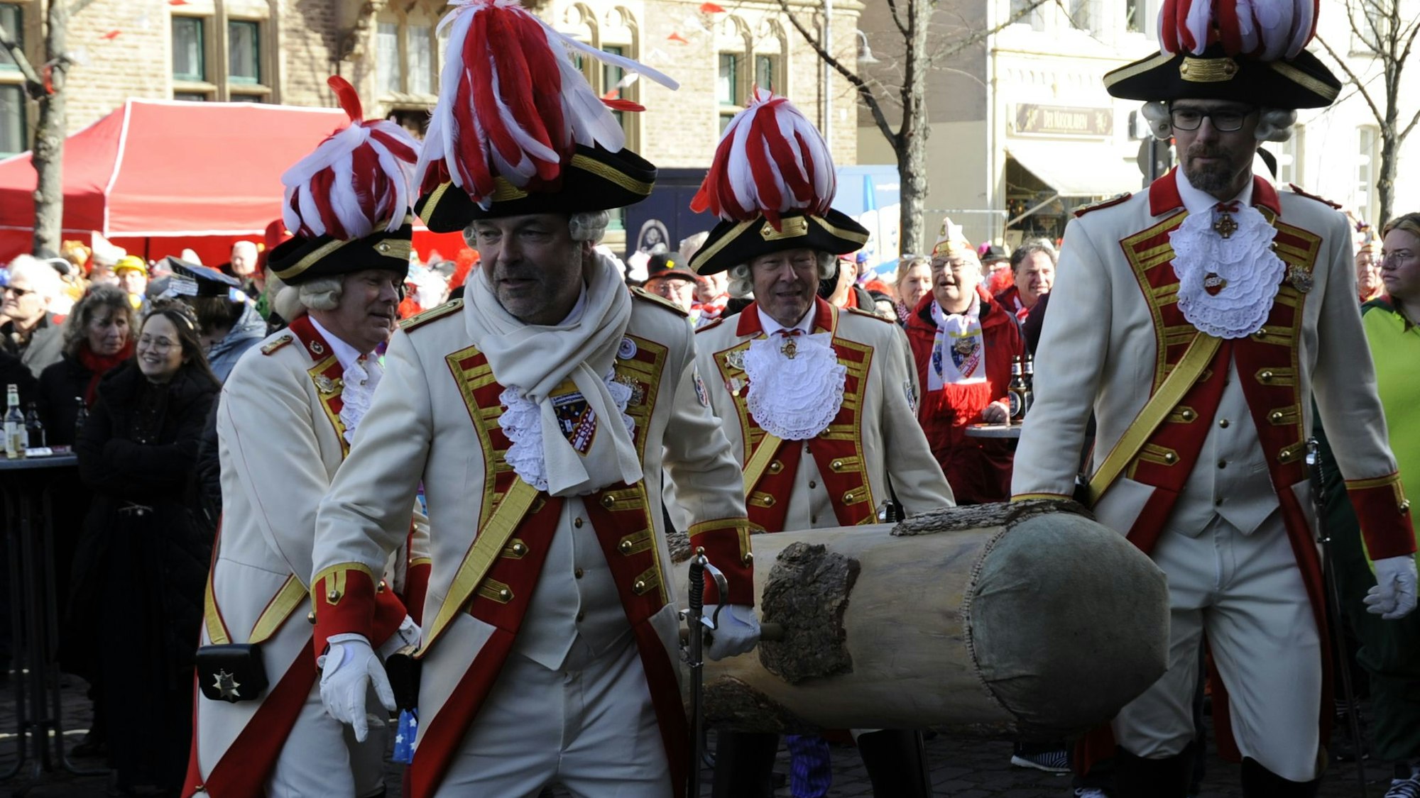Vier Männer tragen einen Rammbock.
