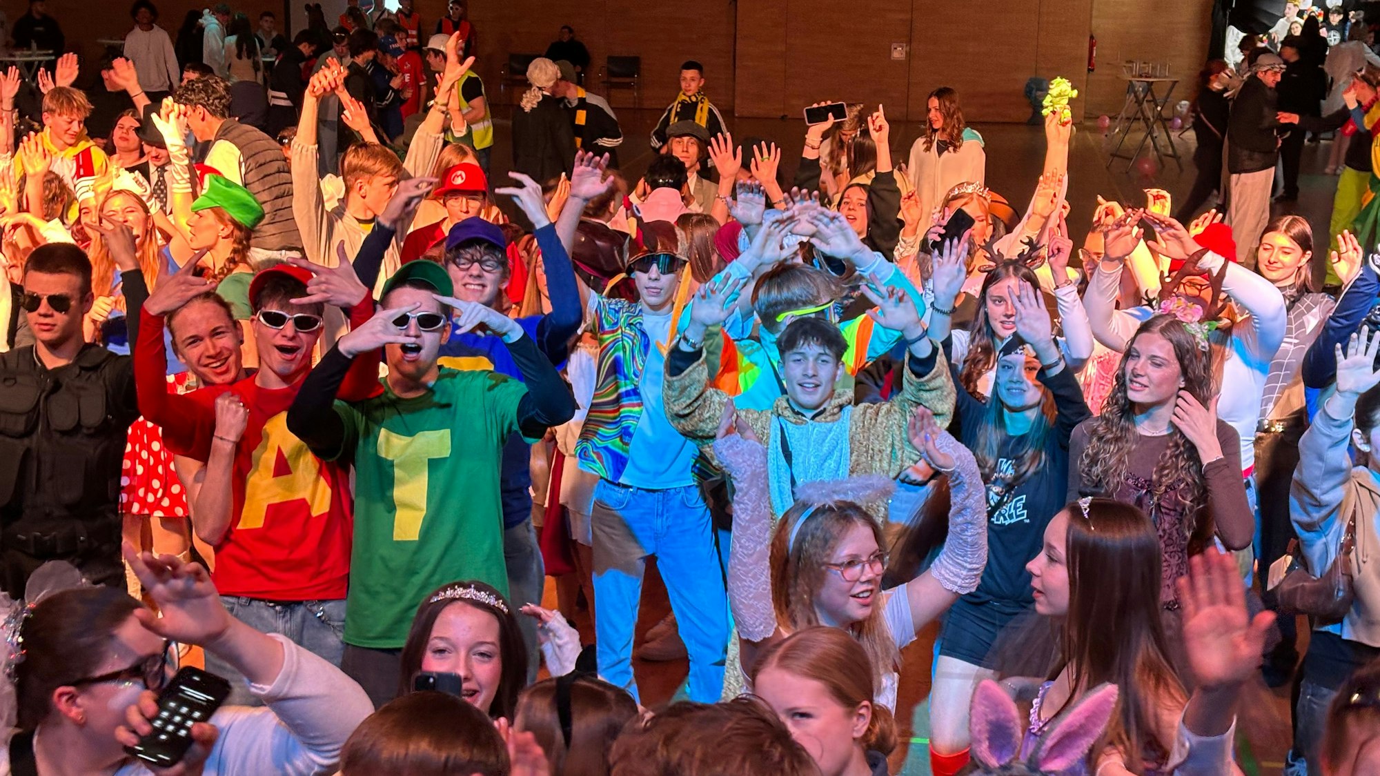 Eine jugendliche Menge hebt die Arme in einem Saal.