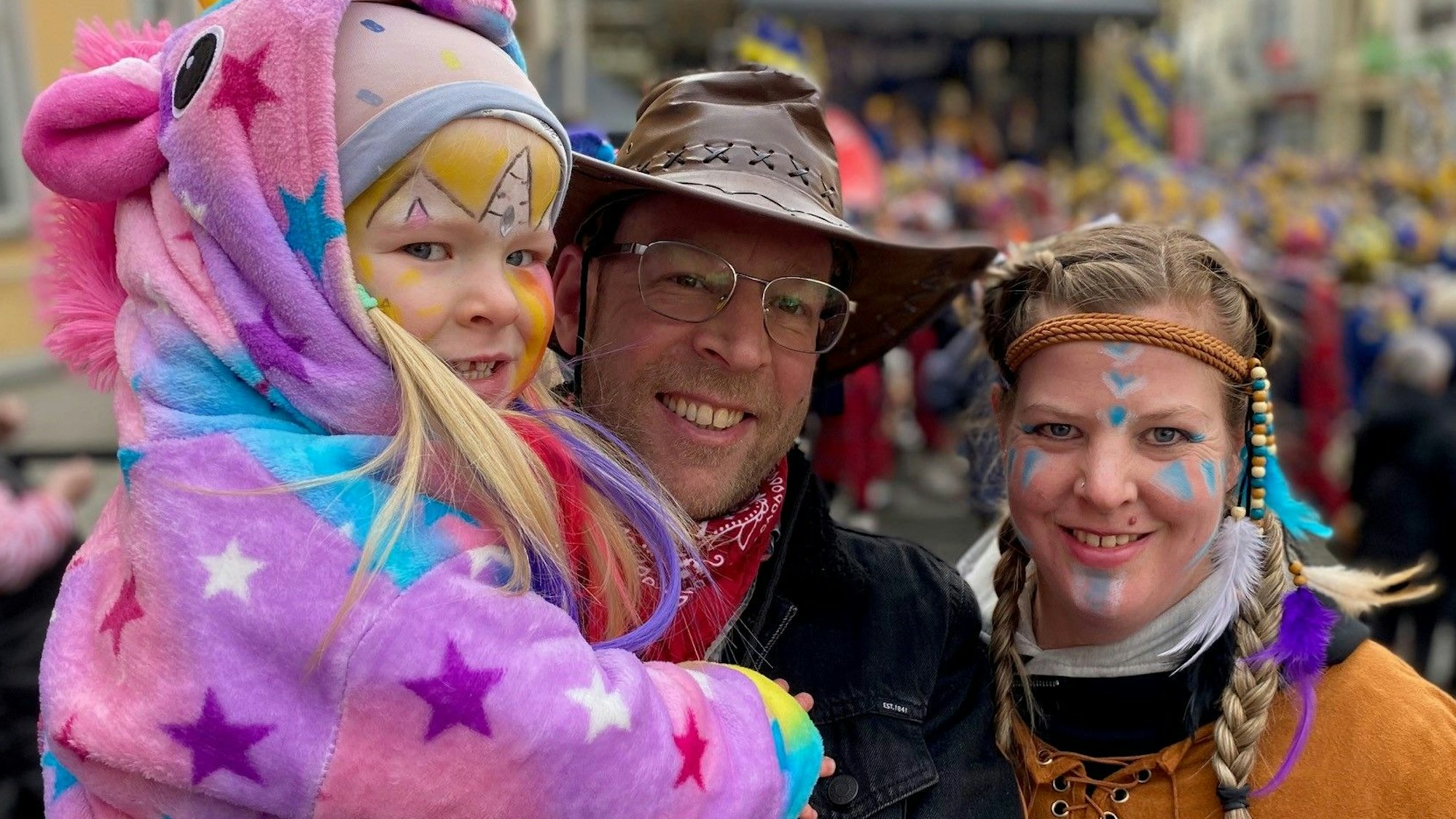 Zu sehen ist eine dreiköpfige, kostümierte Familie.