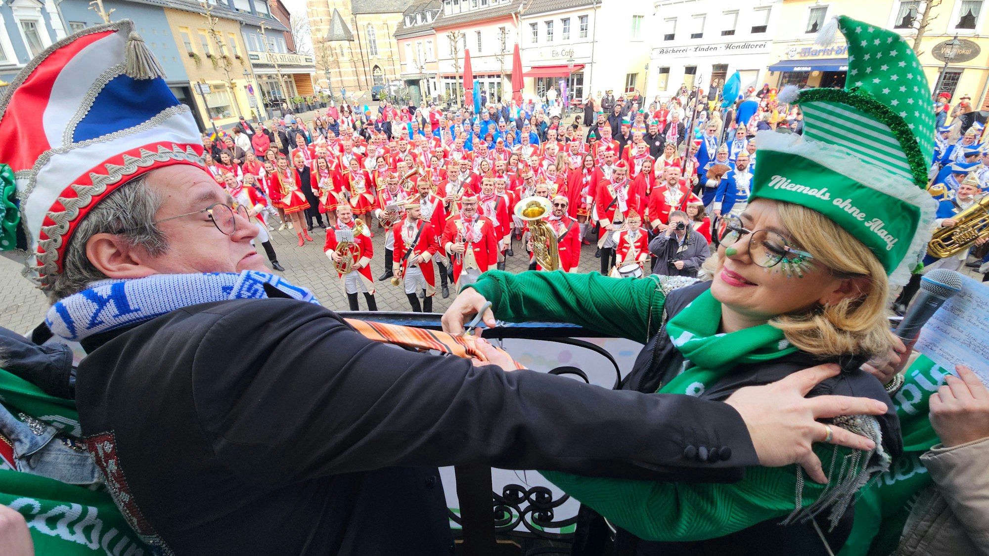 Zu sehen ist, wie eine kostümierte Frau Bedburgs Bürgermeister Sascha Solbach die Krawatte abschneidet.