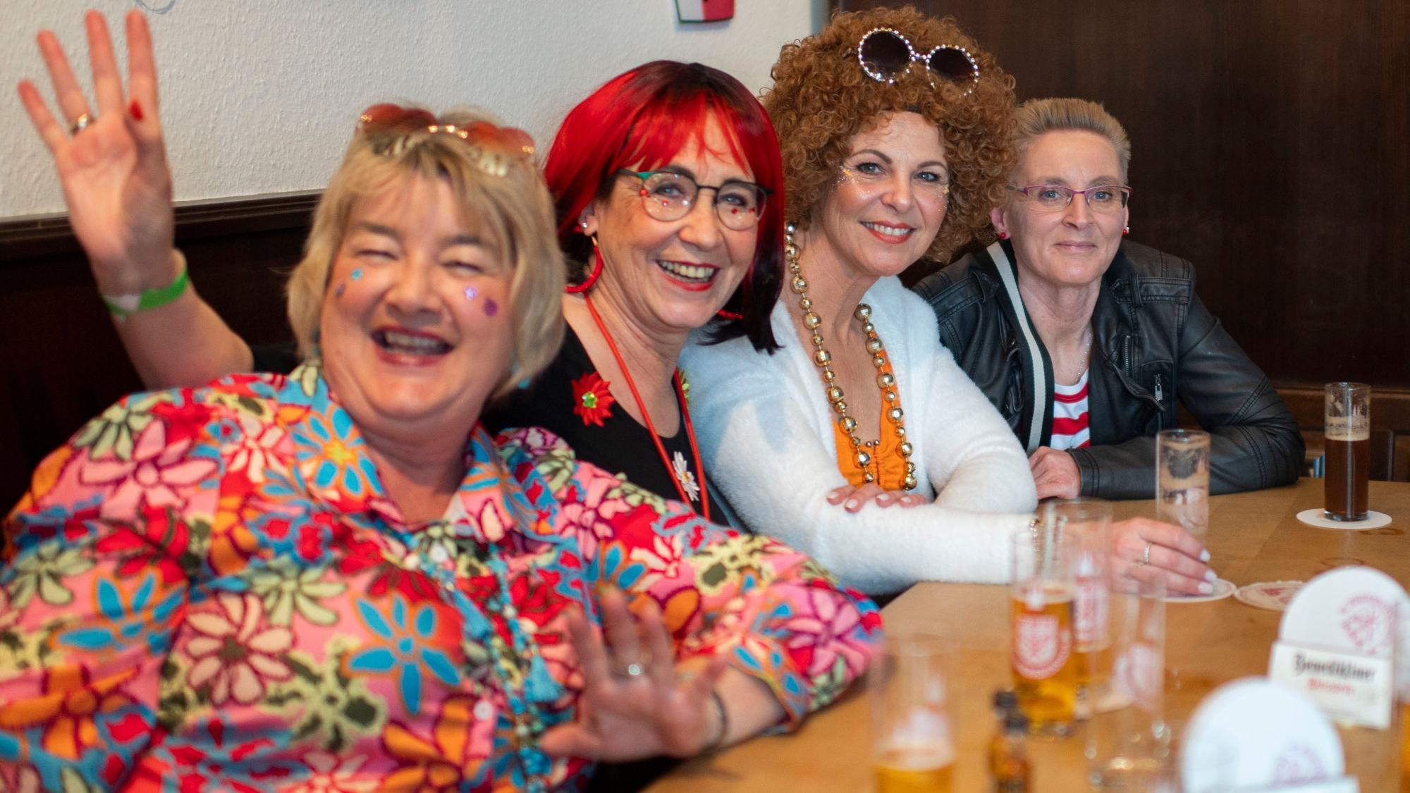 Das Bild zeigt vier Frauen, die an einem Tisch sitzen. Sie lächeln in die Kamera.