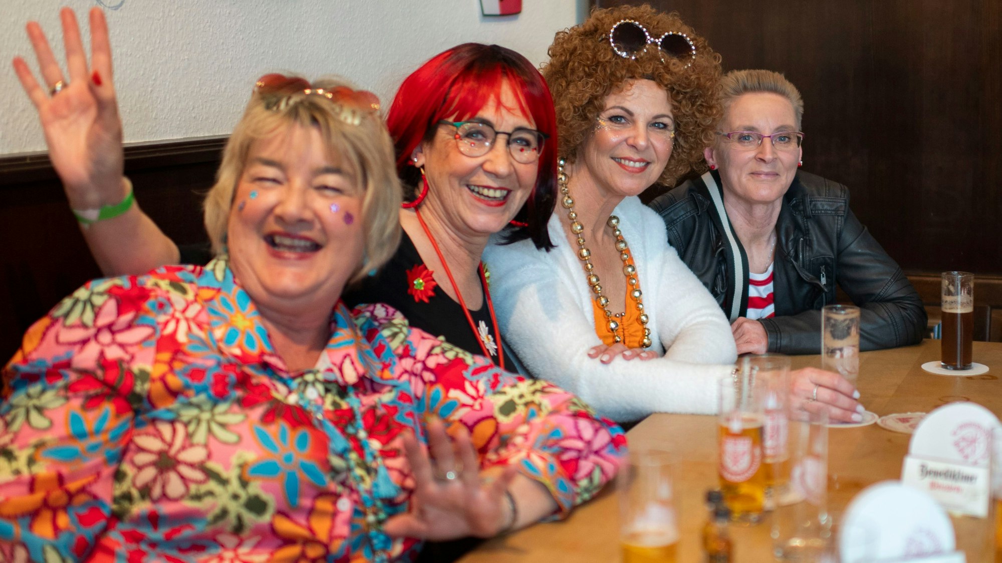 Das Bild zeigt vier Frauen, die an einem Tisch sitzen. Sie lächeln in die Kamera.